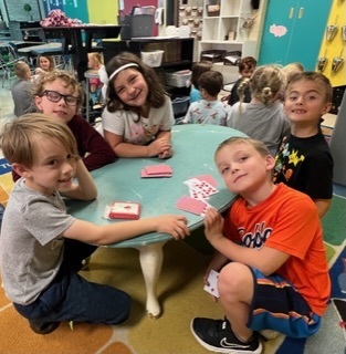 students sitting at a table in the classroom playing a card game