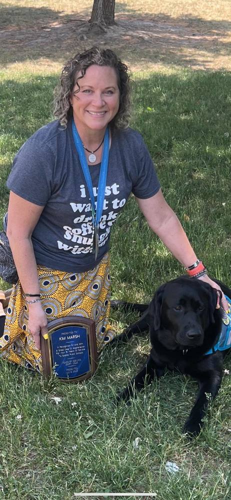 Kim Marsh holding Retirement plaque with her Therapy Dog  Cooper