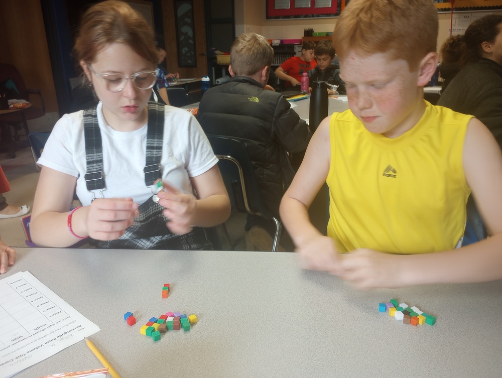 Two students using math unit cubes to figure out volume in 5th grade classroom